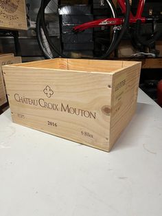 a wooden box sitting on top of a table next to a red bike in the background