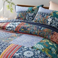 a bed covered in blue and multi colored bedspread