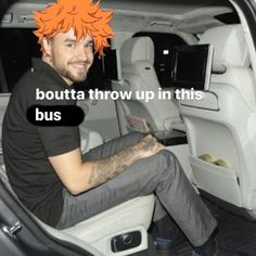 a man sitting in the back seat of a car with an orange mohawk on his head