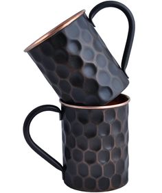 two black and copper mugs stacked on top of each other, one is filled with honey