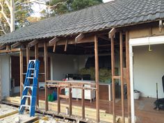 a house being built with the roof ripped off and some tools on the ground next to it