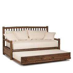 a wooden daybed with white pillows and a pull out sofa bed underneath the mattress