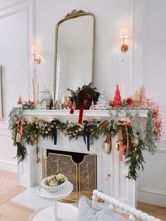 a mantel decorated for christmas with greenery and bows on it's mantle