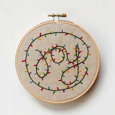 an embroidered hoop with the letter s on it and colorful thread sprinkles