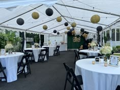 tables and chairs are set up under a white tent with black and gold decorations on it