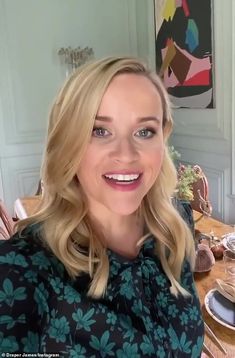 a woman sitting at a table smiling for the camera