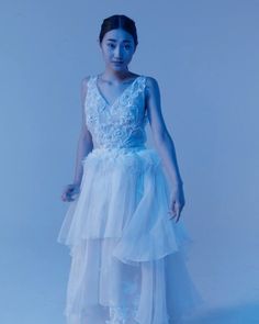 a woman in a white dress standing against a blue background