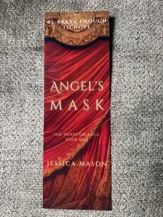 the book angel's mask is laying on top of a carpeted floor with its cover pulled back