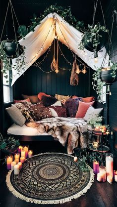 a bed with lots of pillows and candles on the floor in front of an area rug