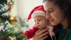 a woman holding a baby wearing a santa hat