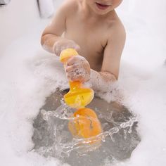 a young boy playing in the bathtub with soap on his hands and oranges