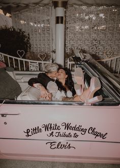 an older couple kissing in the back of a pink convertible car that says, little white wedding chapel