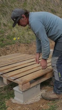 a man is working on a bench made out of pallets and wood planks