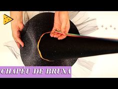 a woman is making a hat out of black fabric and gold thread with her hands