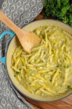 a wooden spoon in a blue pan filled with pasta