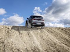 a car driving on top of a pile of dirt in the middle of a field