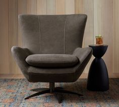 a gray chair sitting next to a black table on top of a carpeted floor