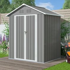 a small shed sitting on top of a wooden deck next to a fence and flowers