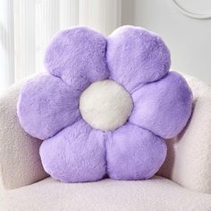 a purple flower pillow sitting on top of a white chair