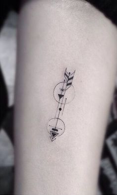 a black and white photo of a woman's leg with an arrow tattoo on it