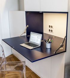 a laptop computer sitting on top of a desk next to a glass chair and lamp