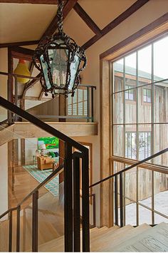 a chandelier hanging from the side of a wooden staircase next to a window