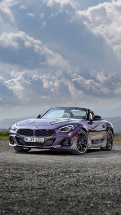 the bmw z4 roadster convertible is parked in front of a mountain range under a cloudy sky