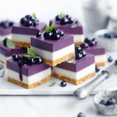 small desserts with blueberries and cream are arranged on a white plate next to spoons