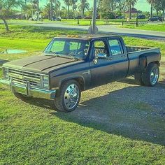 an old pick up truck parked on the side of a road in front of some palm trees