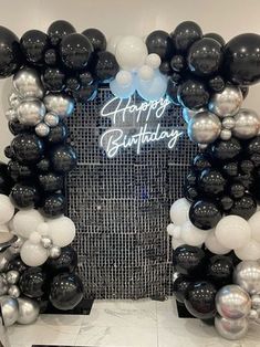 an arch made out of balloons with the words happy birthday written in white and black