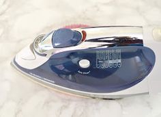 a blue and white steam iron sitting on top of a marble countertop next to a bottle opener