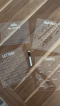 three clear plastic name tags on a wooden table with a black marker and some writing paper