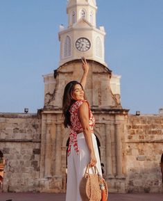 a woman standing in front of a clock tower