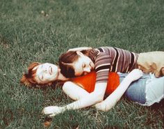 two young women laying on the grass in front of each other with their eyes closed