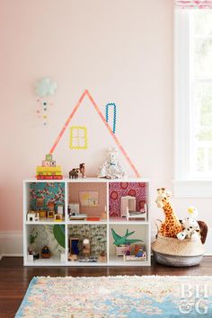 a room with pink walls and a white bookcase filled with toys on top of it