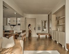 a woman is standing in the middle of a living room with wood floors and white walls