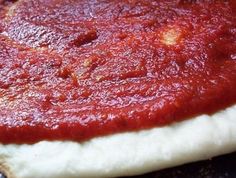 a pizza crust covered in marinara sauce