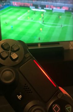 a video game controller in front of a television with a soccer match on the screen