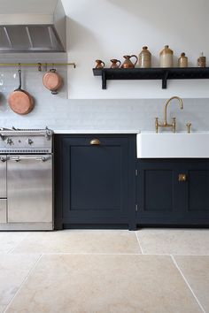 a kitchen with blue cabinets and white counter tops, gold faucets and pots on the wall