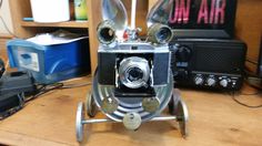 an old fashioned camera sitting on top of a wooden table next to other electronic equipment