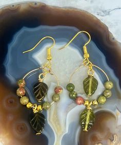 Embrace nature's beauty with these exquisite handmade hoop earrings featuring detailed green leaf charms and earthy unakite gemstone beads. The warm gold accents add a touch of elegance, making these earrings perfect for any occasion, from casual outings to special events. Each earring showcases: *Green leaf Czech glass charms: Beautifully detailed for a natural, organic look. *Gemstone beads: Unakite: A blend of earthy tones with hints of red and green, inspired by nature's palette. *Gold-tone Handmade Nature-inspired Dangle Beaded Earrings, Natural Dangle Earrings, Nature-inspired, Multicolor Earthy Dangle Earrings, Nature-inspired Brown Dangle Earrings, Handmade Hoop Earrings, Bohemian Brown Leaf-shaped Earrings, Glass Charms, Beaded Hoop Earrings, Beaded Hoops