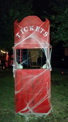 an old fashioned ticket booth is covered in plastic and sits on the grass at night