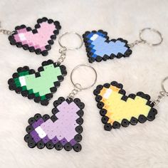 four pixel heart shaped keychains on a white furnishing with black beads