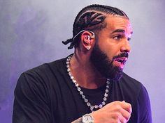 a man with dreadlocks and a watch on his left hand is speaking into a microphone