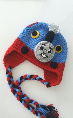 a crocheted hat with a blue and red train on the front, sitting on top of a white surface