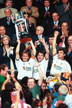 a group of men holding up a trophy in front of a crowd