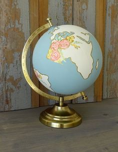 a globe with flowers painted on it sitting on a wooden table next to a wall