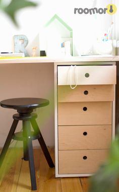 a wooden desk with drawers and a stool in front of it on top of a hard wood floor