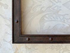 an old metal frame with rivets on a wallpapered background is shown