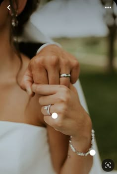 a woman in a white dress holding onto her wedding ring